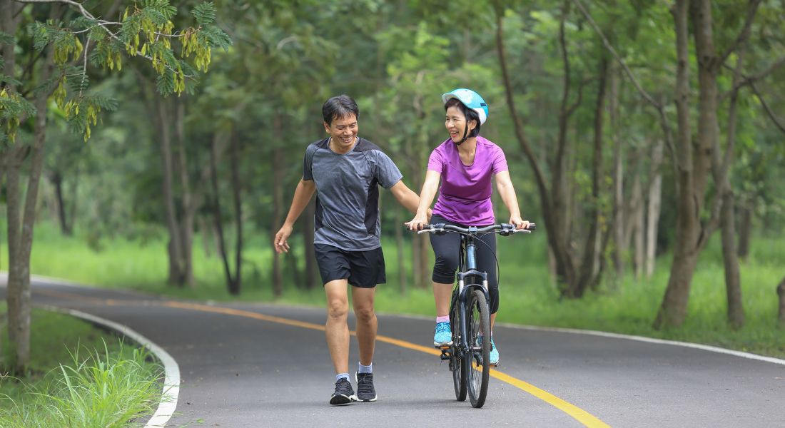 Woman riding bike with. man running along side her.