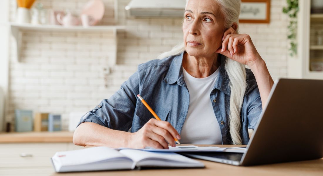 Woman in front of a laptop taking notes.